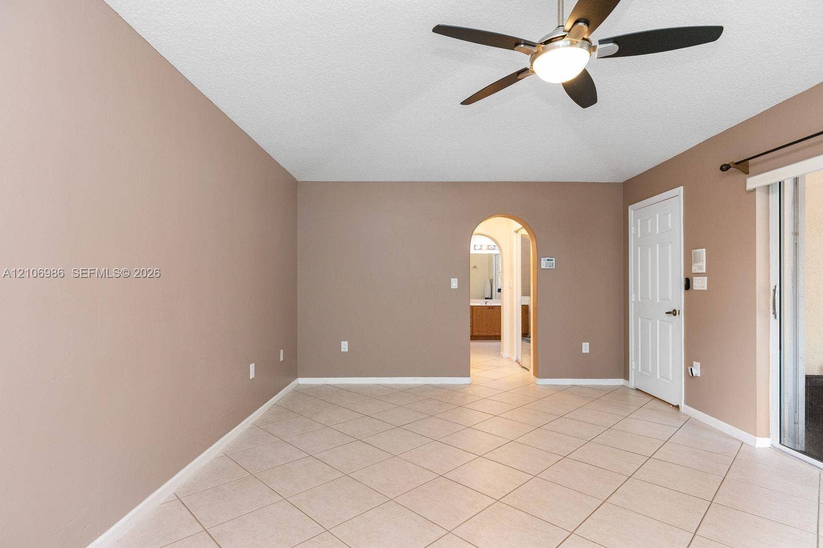 3801 SW 147th Avenue, Miramar, FL 33027 Room featuring ceramic tile flooring, a multi-blade ceiling fan with integrated lighting, a structural arched doorway, and a sliding glass door