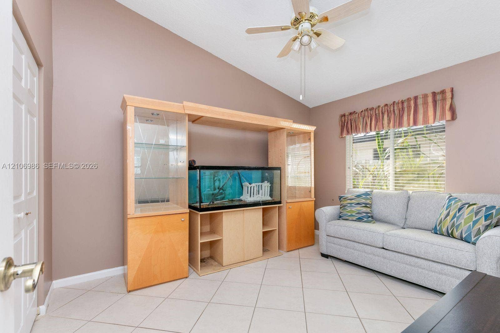3801 SW 147th Avenue, Miramar, FL 33027 Room featuring vaulted ceilings, light-tone tile flooring, built-in wooden cabinetry with glass-paneled display shelving, and a ceiling fan