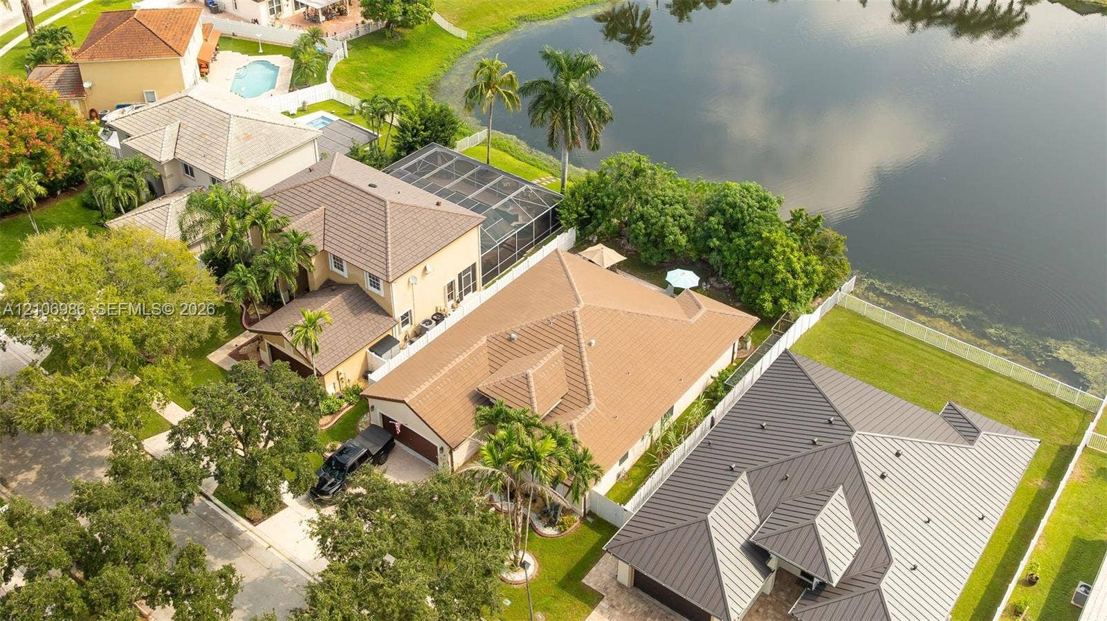 3801 SW 147th Avenue, Miramar, FL 33027 Aerial perspective featuring a tile roof, concrete driveway, attached multi-car garage, mature landscaping, and water frontage