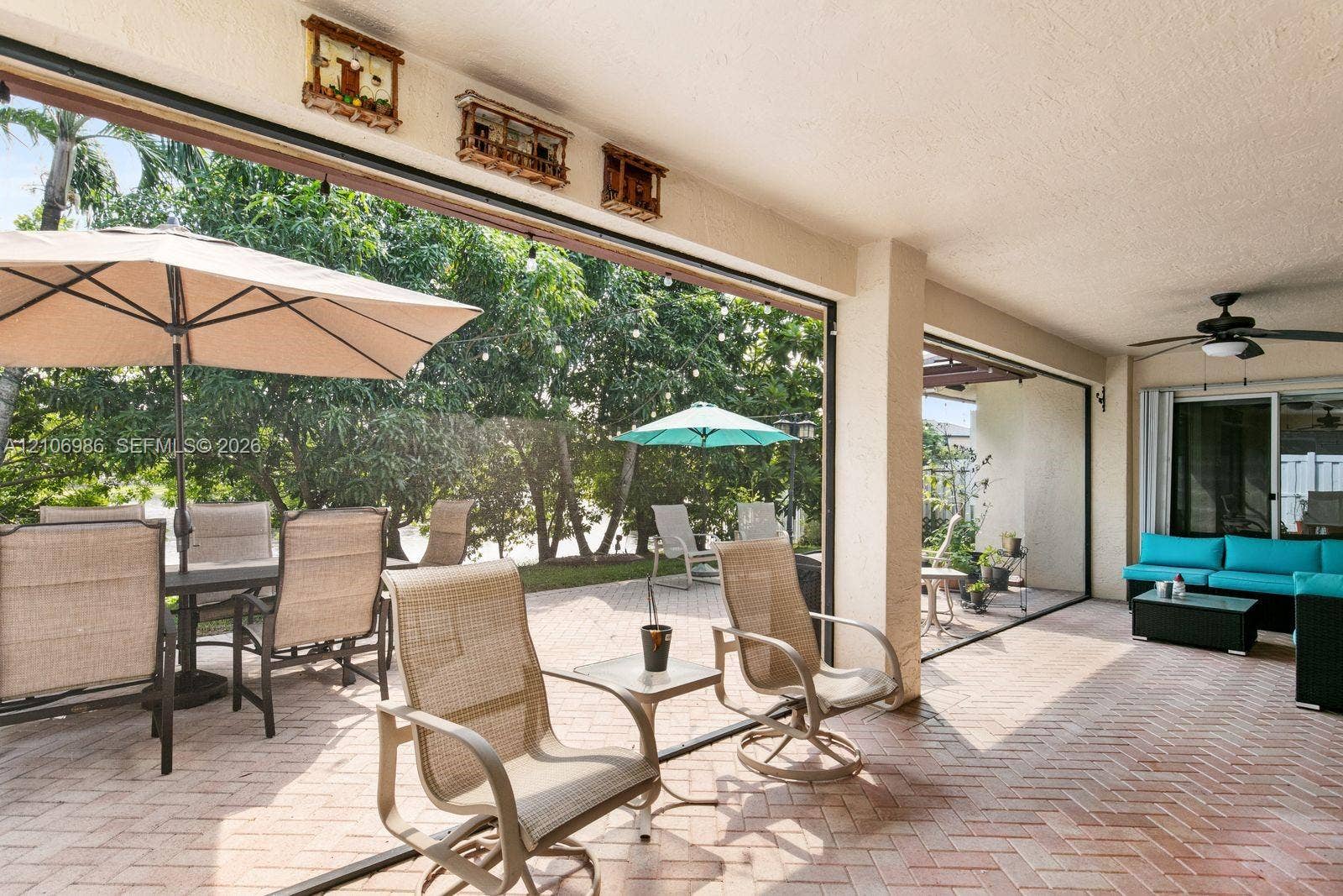 3801 SW 147th Avenue, Miramar, FL 33027 Covered patio featuring herringbone-patterned brick pavers, ceiling-mounted paddle fan, and large-format sliding glass door system