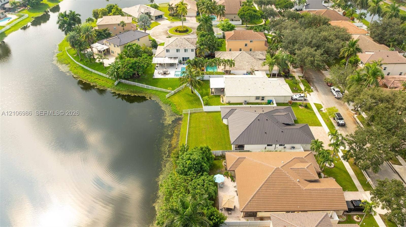 3801 SW 147th Avenue, Miramar, FL 33027 Aerial perspective of a waterfront residential area featuring mature landscaping, tile-roofed properties, private fenced backyards, and expansive water frontage