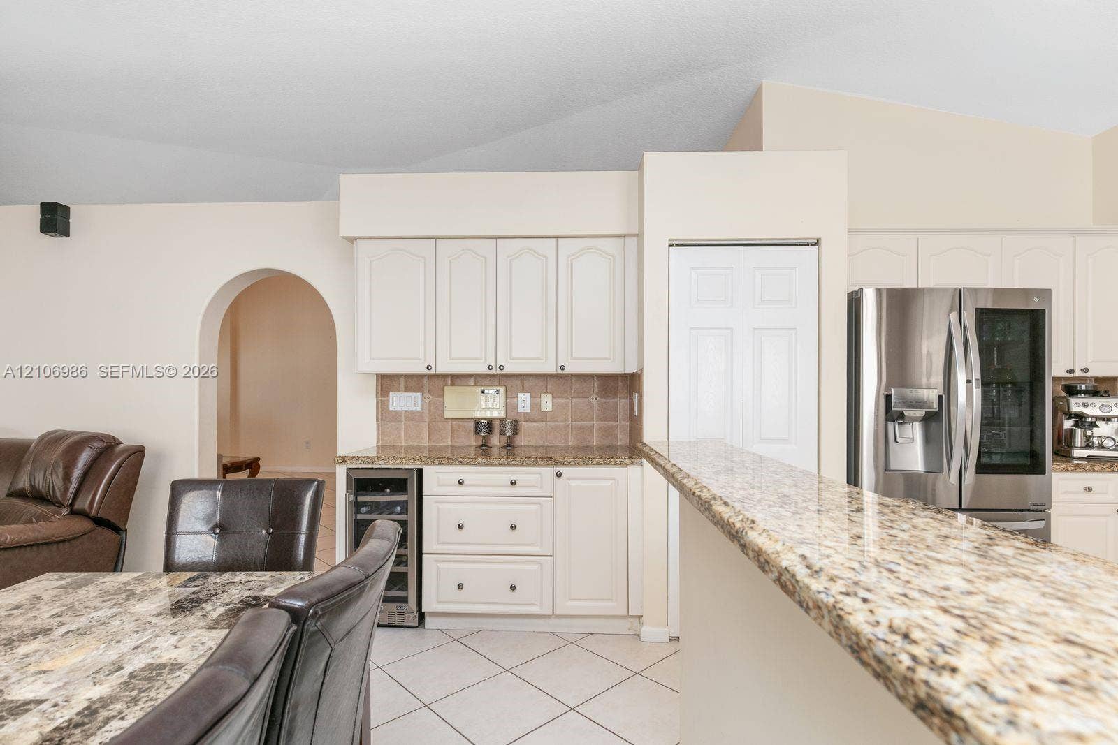 3801 SW 147th Avenue, Miramar, FL 33027 Kitchen featuring white cabinetry, stone-finish countertops, built-in wine cooler, stainless steel refrigerator, and arched doorway
