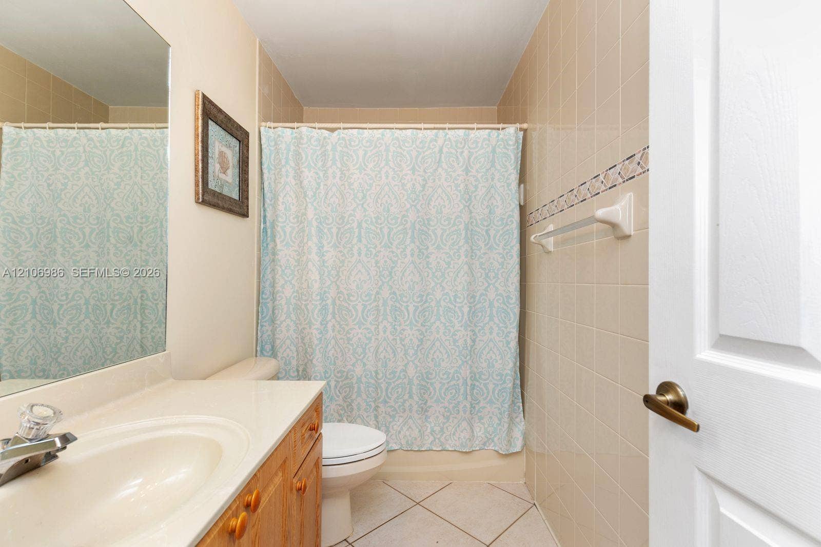 3801 SW 147th Avenue, Miramar, FL 33027 Bathroom featuring a wooden vanity with a stone countertop, an integrated sink, a large wall-mounted mirror, and tile flooring with decorative wall tile accents
