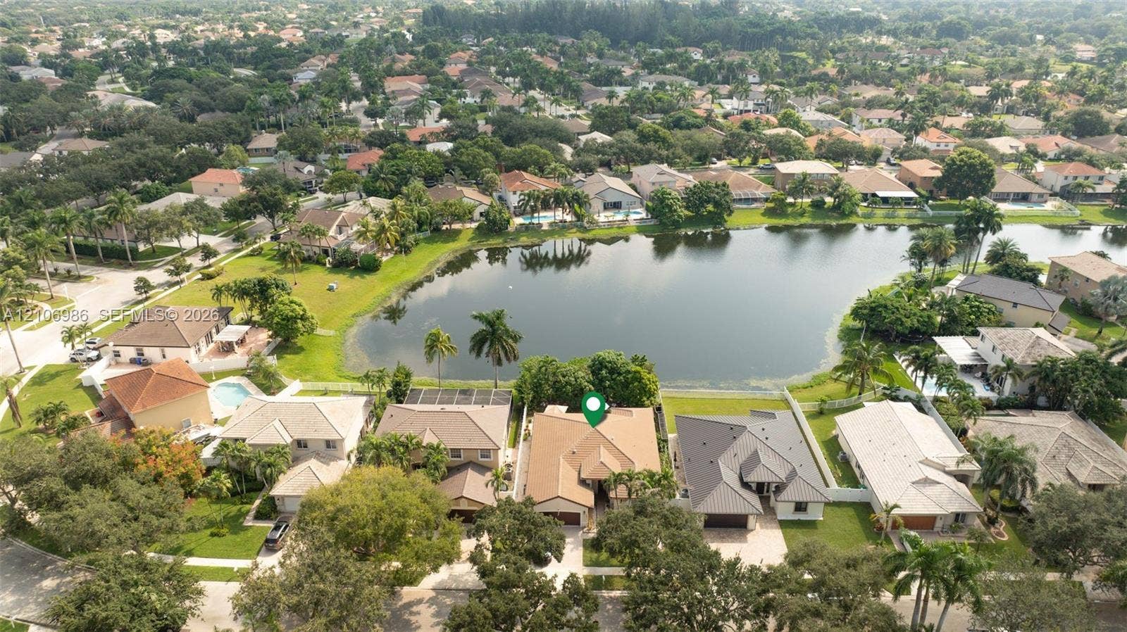 3801 SW 147th Avenue, Miramar, FL 33027 Aerial perspective featuring a waterfront property with a concrete tile roof, paved driveway, and mature landscaping