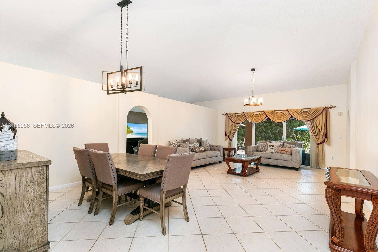3801 SW 147th Avenue, Miramar, FL 33027 Open-concept floor plan featuring tile flooring, vaulted ceilings, dual decorative pendant light fixtures, and an arched entryway