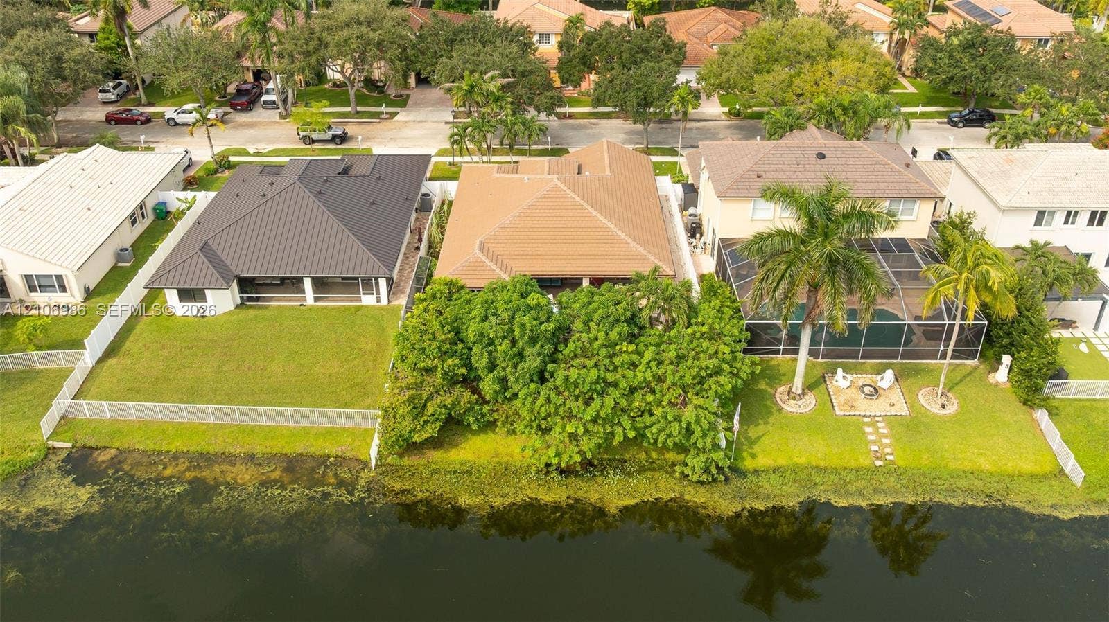 3801 SW 147th Avenue, Miramar, FL 33027 Waterfront residential lot featuring a manicured lawn, established landscaping, and perimeter fencing