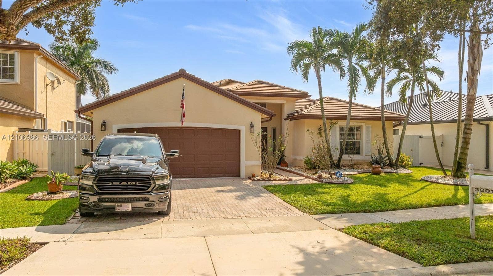 3801 SW 147th Avenue, Miramar, FL 33027 Stucco exterior with a tiled roof, paver driveway, two-car garage, and established palm tree landscaping