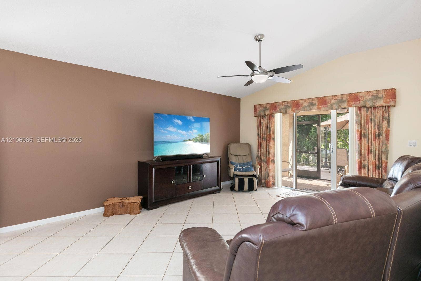 3801 SW 147th Avenue, Miramar, FL 33027 Living area with vaulted ceilings, neutral tile flooring, a stainless steel and glass ceiling fan, and sliding glass doors with exterior access