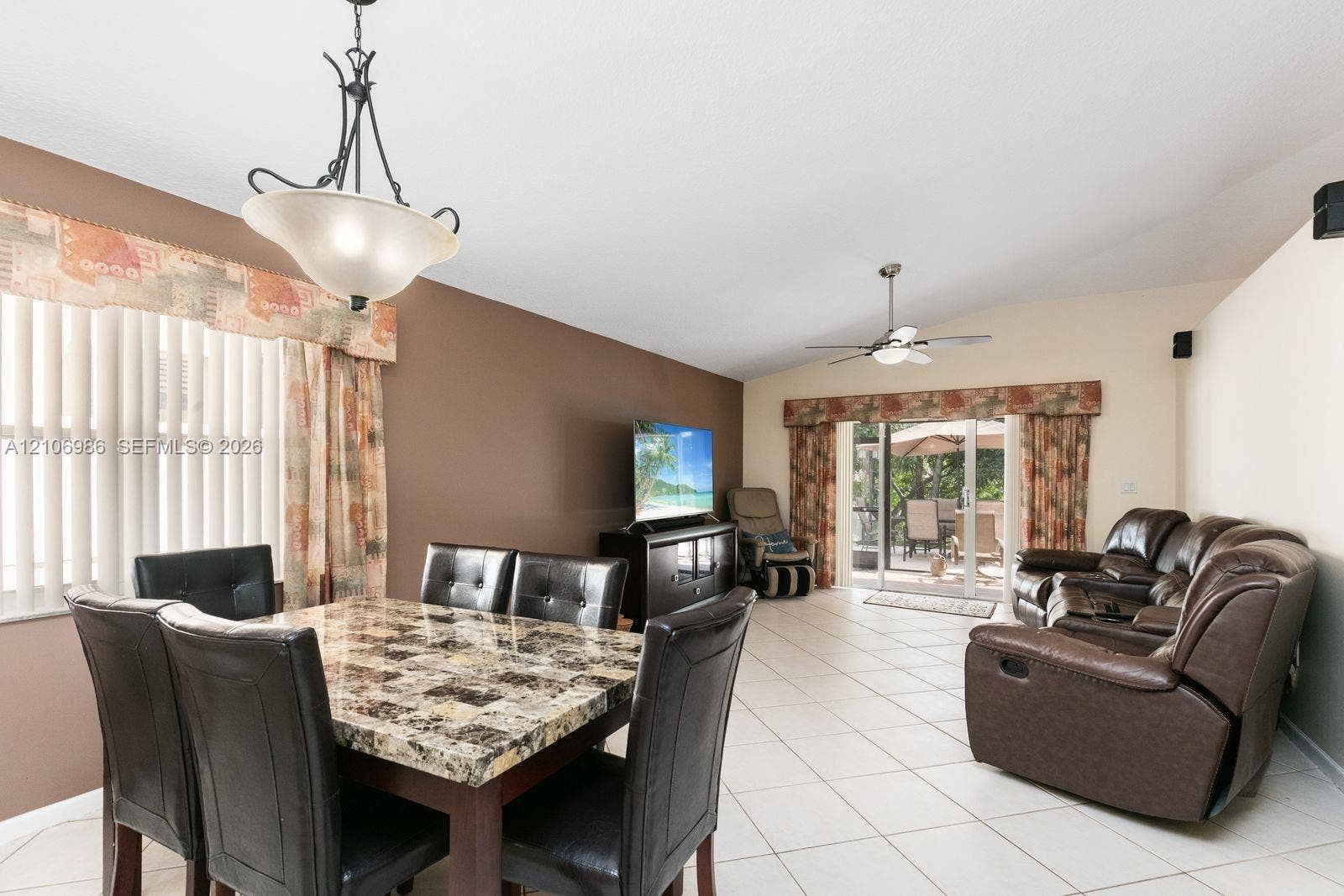 3801 SW 147th Avenue, Miramar, FL 33027 Open-concept area featuring light-toned tile flooring, vaulted ceilings, a central ceiling fan with integrated lighting, and glass sliding doors providing exterior access
