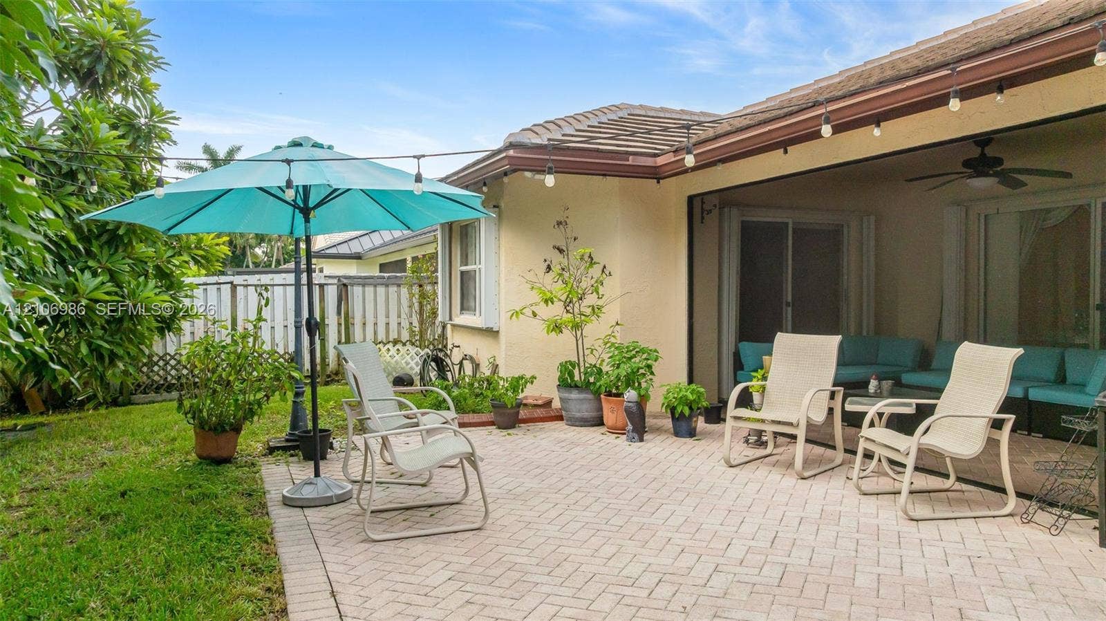 3801 SW 147th Avenue, Miramar, FL 33027 Covered patio with paver flooring, overhead ceiling fan, and string lighting, complemented by a dedicated exterior paver area