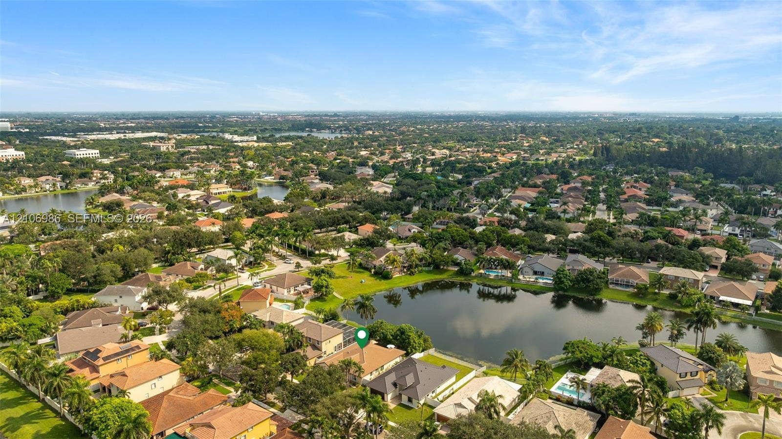 3801 SW 147th Avenue, Miramar, FL 33027 Aerial perspective of a property situated on a lakefront lot featuring a multi-pitched roofline, palm trees, and mature landscaping
