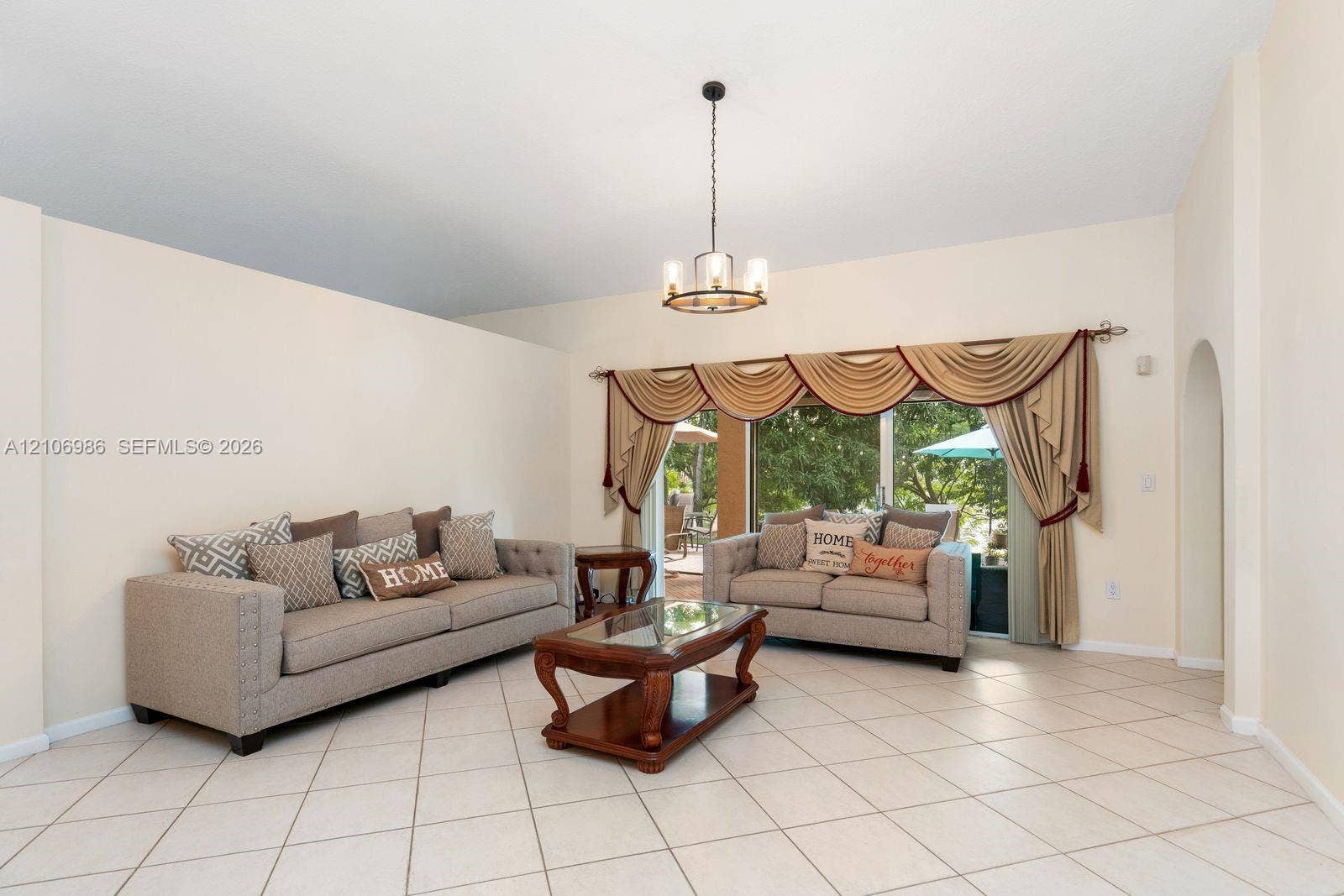 3801 SW 147th Avenue, Miramar, FL 33027 Living area featuring high ceilings, neutral wall tones, diagonal-set ceramic tile flooring, a multi-arm metal chandelier, and a sliding glass door