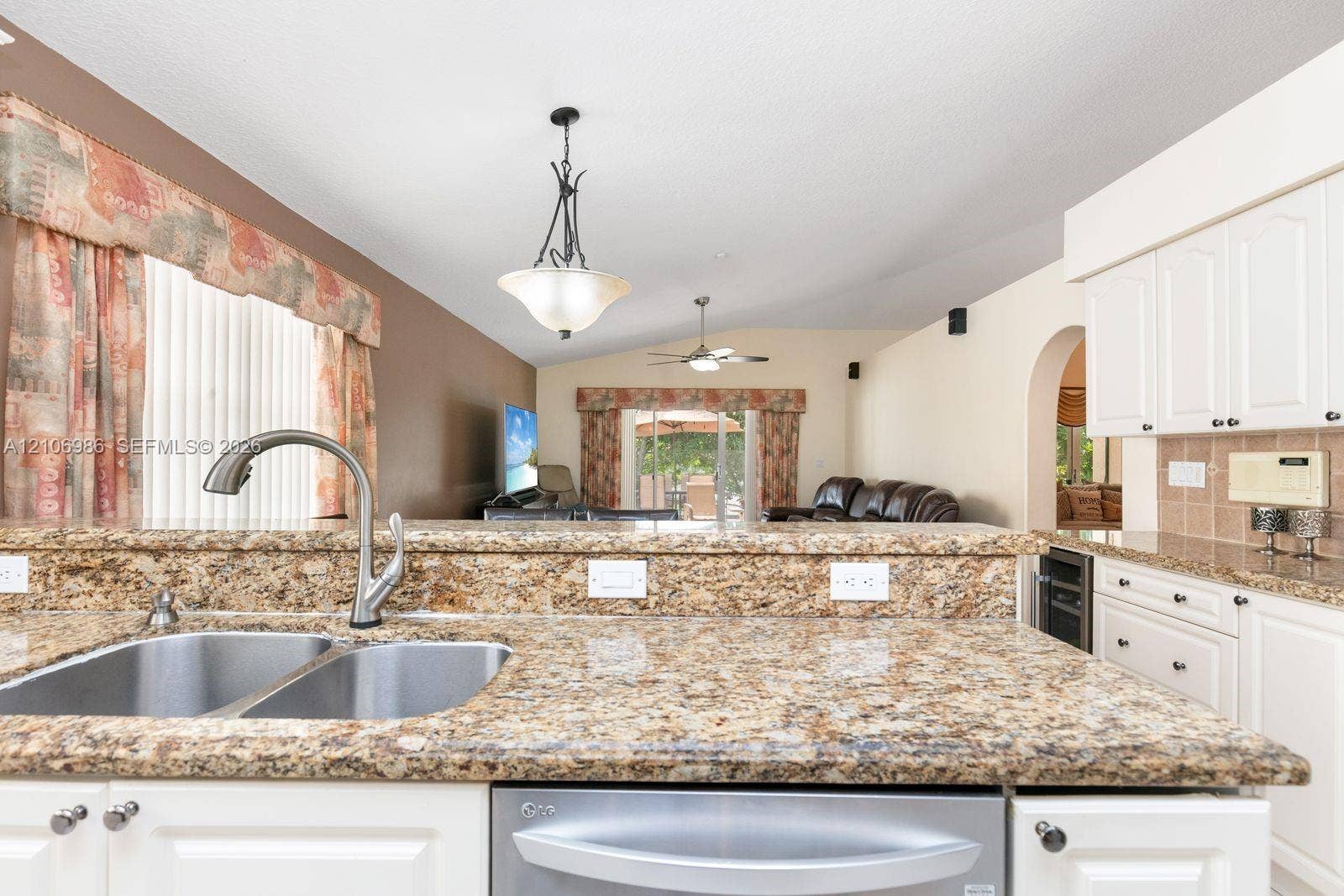 3801 SW 147th Avenue, Miramar, FL 33027 Kitchen featuring stone countertops, a dual-basin stainless steel sink with a high-arch faucet, white cabinetry, a built-in wine refrigerator, and decorative pendant lighting