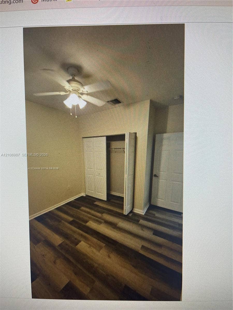 Room featuring wood-finish flooring, a ceiling fan with integrated lighting, and a closet with bifold doors