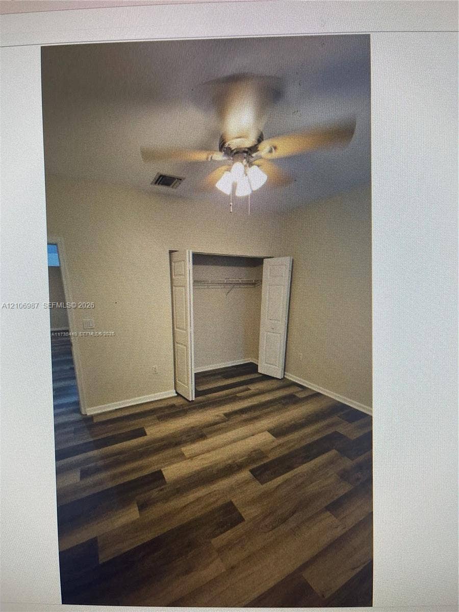 Interior space featuring wood-finish flooring, a ceiling fan with integrated light fixture, and a closet with bifold doors