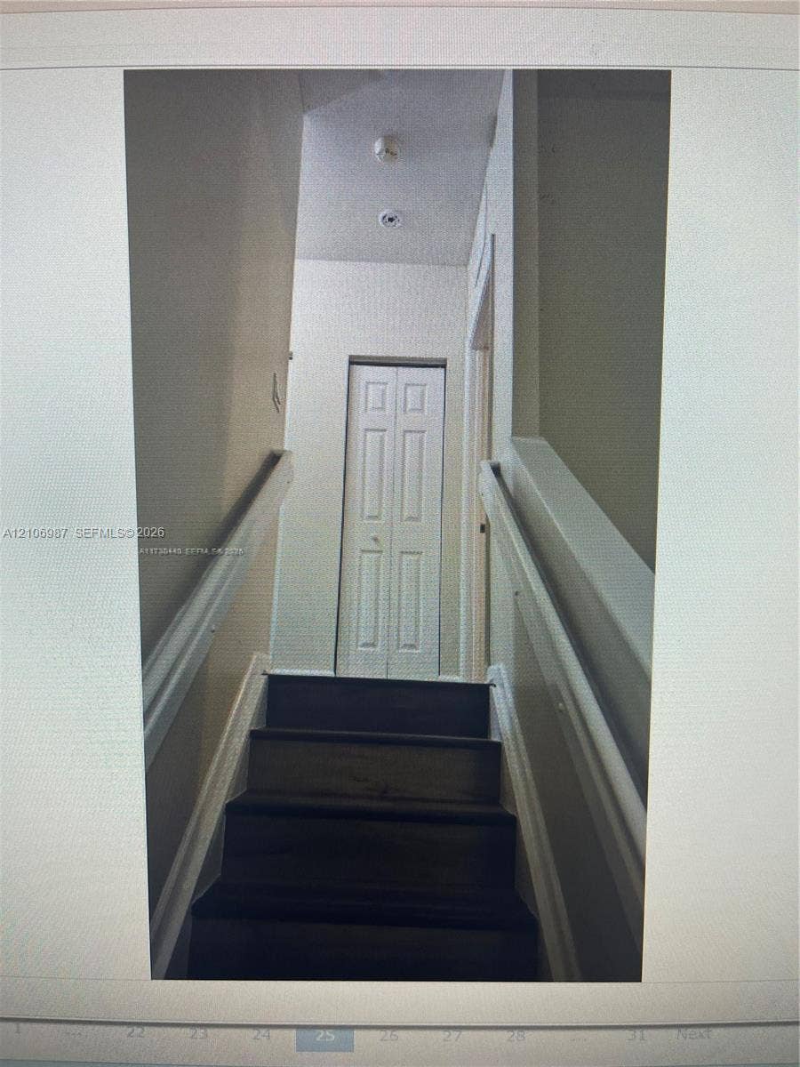 Staircase featuring wood-finish treads, white painted railings, and a bi-fold closet door