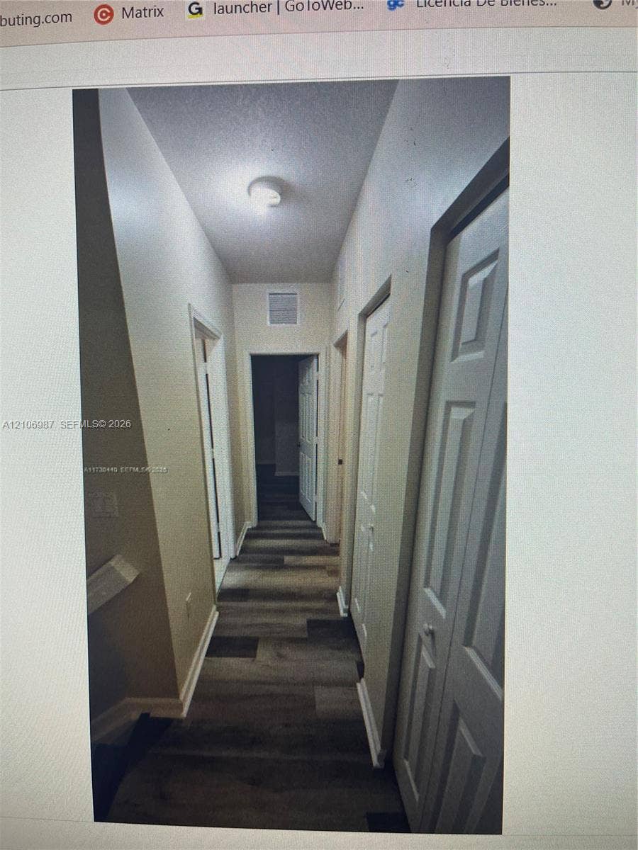 Hallway featuring wood-finish flooring, white panel doors, and ceiling-mounted light fixture