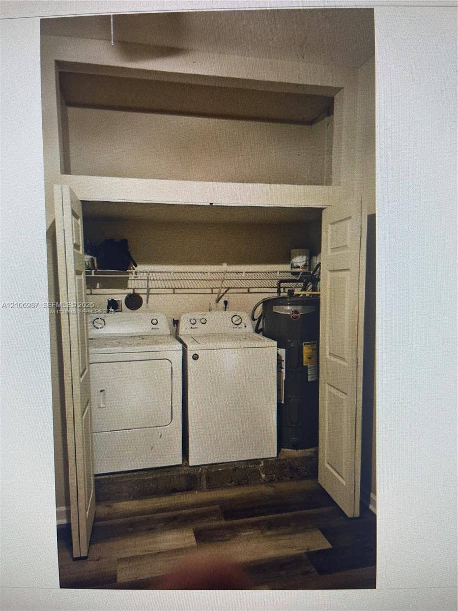 Laundry closet featuring bifod doors, wire shelving, wood-finish flooring, and a dedicated utility space