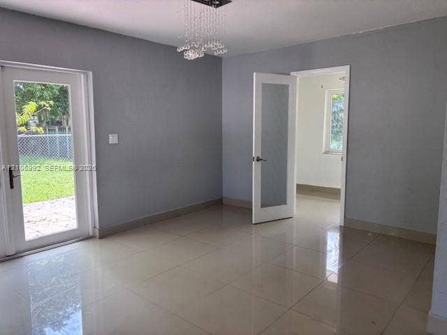 Large-format polished tile flooring, crystal chandelier lighting, glass-paneled entry door, and interior glass-panel door