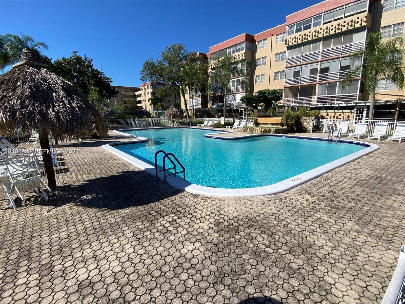 410 NW 68th Avenue, #515, Plantation, Plantation, FL 33317 Swimming pool with integrated steps, surrounded by a paved patio, thatched-roof cabana, and multi-story building facade