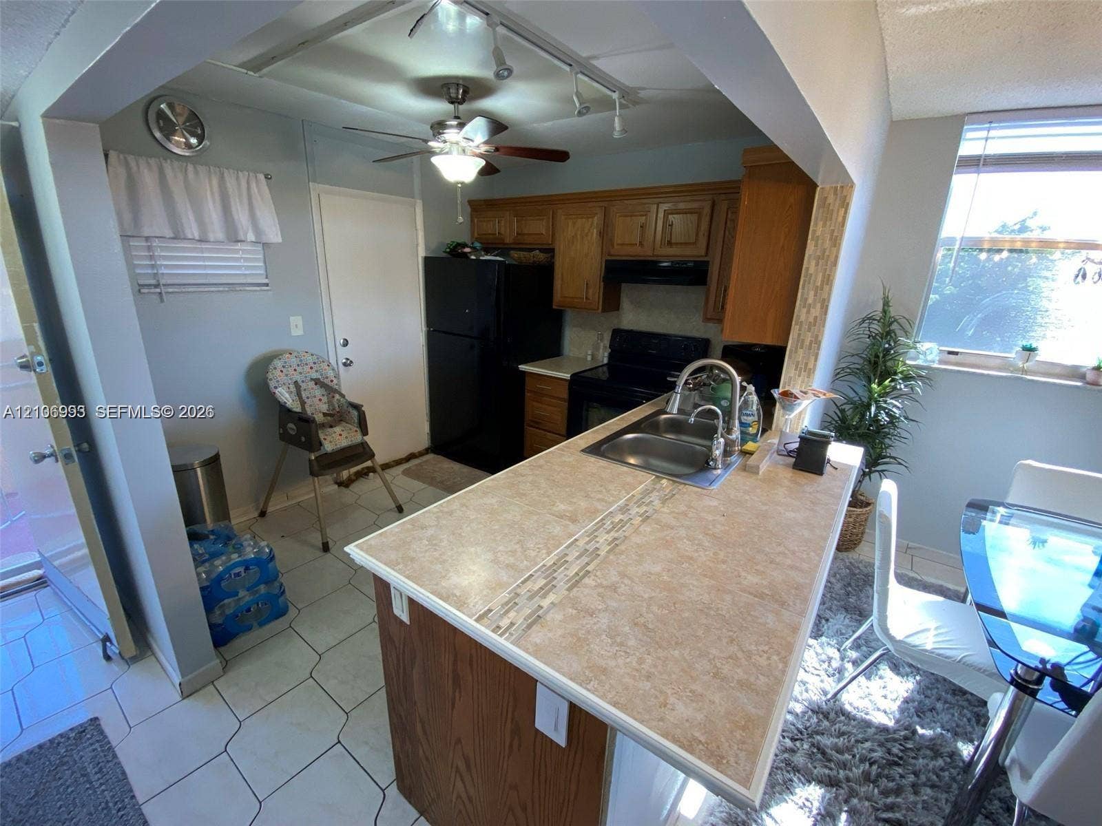 410 NW 68th Avenue, #515, Plantation, Plantation, FL 33317 Kitchen featuring wood cabinetry, a breakfast bar with stone-finish countertop, dual-basin stainless steel sink with pull-down faucet, and ceramic tile flooring