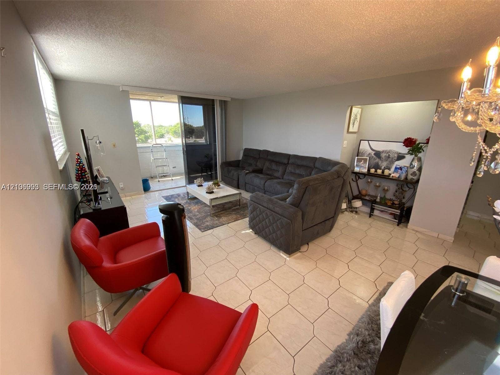 410 NW 68th Avenue, #515, Plantation, Plantation, FL 33317 Living area featuring hexagonal tile flooring, decorative chandelier, and sliding glass door access to an exterior balcony