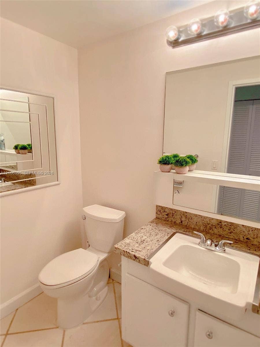 3505 S Ocean Drive, #1404, Hollywood, FL 33019 Bathroom featuring a vanity with a stone-finish countertop, undermount sink, multi-bulb overhead lighting, oversized wall mirror, and neutral tile flooring