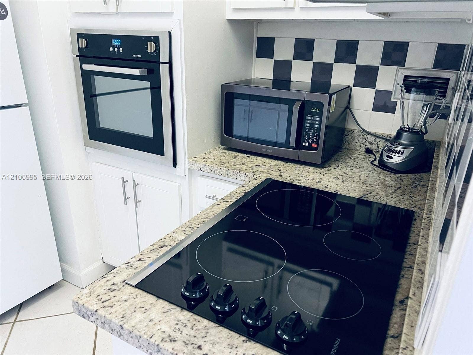 3505 S Ocean Drive, #1404, Hollywood, FL 33019 Kitchen featuring stone countertops, white cabinetry, a built-in wall oven, a glass-top electric cooktop, and a checkerboard-pattern backsplash