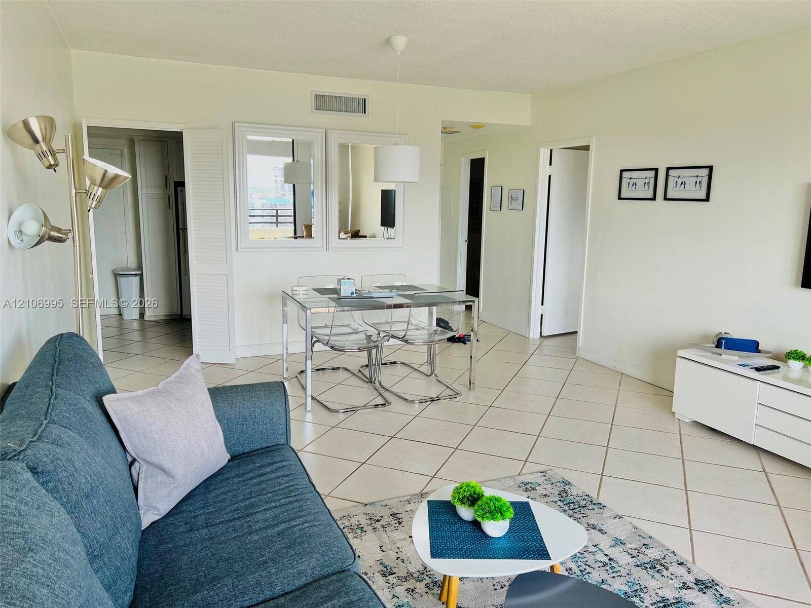 3505 S Ocean Drive, #1404, Hollywood, FL 33019 Open-concept interior featuring neutral tile flooring laid on a diagonal, dual wall-mounted mirrors, and an adjustable pendant lighting fixture