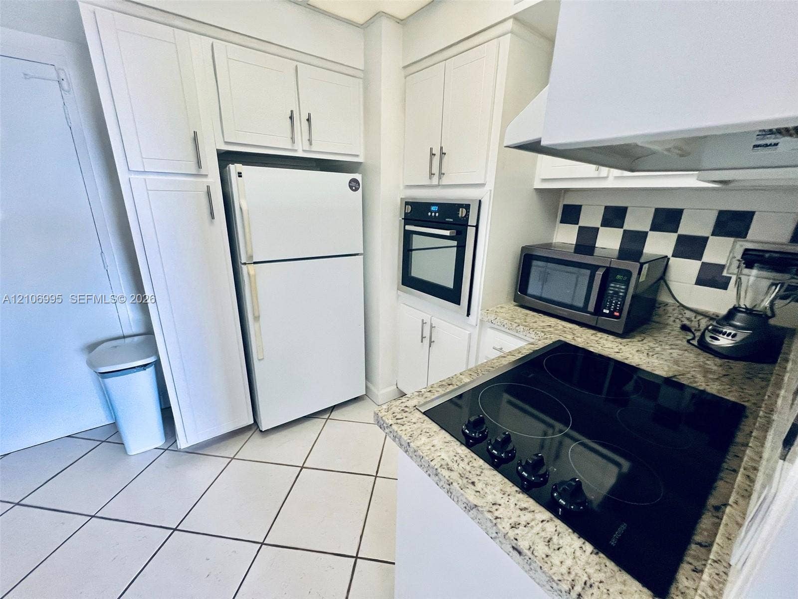 3505 S Ocean Drive, #1404, Hollywood, FL 33019 Kitchen featuring white cabinetry, stone-finish countertops, checkerboard backsplash, built-in oven, and a ceramic cooktop