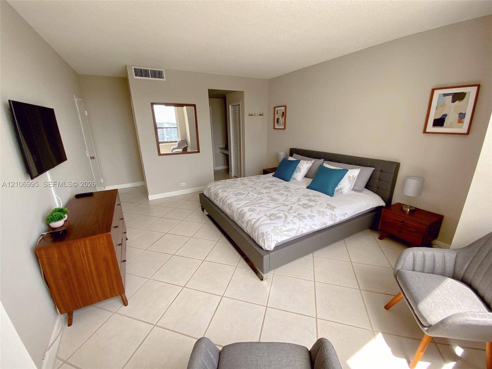 3505 S Ocean Drive, #1404, Hollywood, FL 33019 Neutral-toned interior space featuring light-colored diagonal floor tiling, wall-mounted mirror, and wall-mounted television