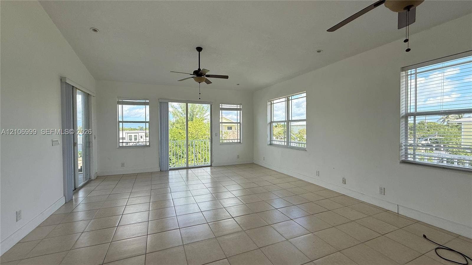 Open-concept interior featuring light-toned tile flooring, recessed lighting, multiple multi-pane windows, and dual ceiling fans