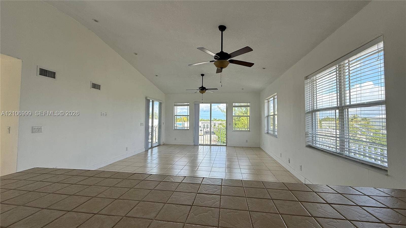 Vaulted ceilings, tile flooring, dual ceiling fans, and multiple large windows with integrated blinds