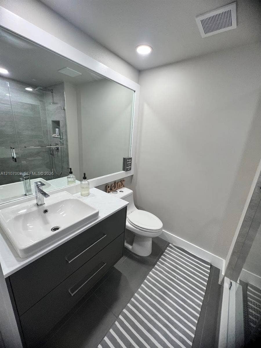 Floating vanity featuring two drawers, a rectangular vessel sink with a chrome faucet, a stone-composite countertop, and a large wall-mounted mirror