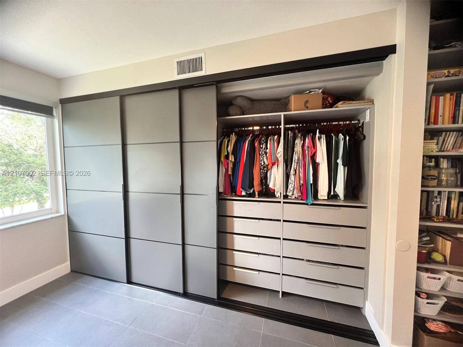 Floor-to-ceiling sliding closet doors with a matte finish, integrated wardrobe organization system, ten soft-close storage drawers, and hanging garment rods