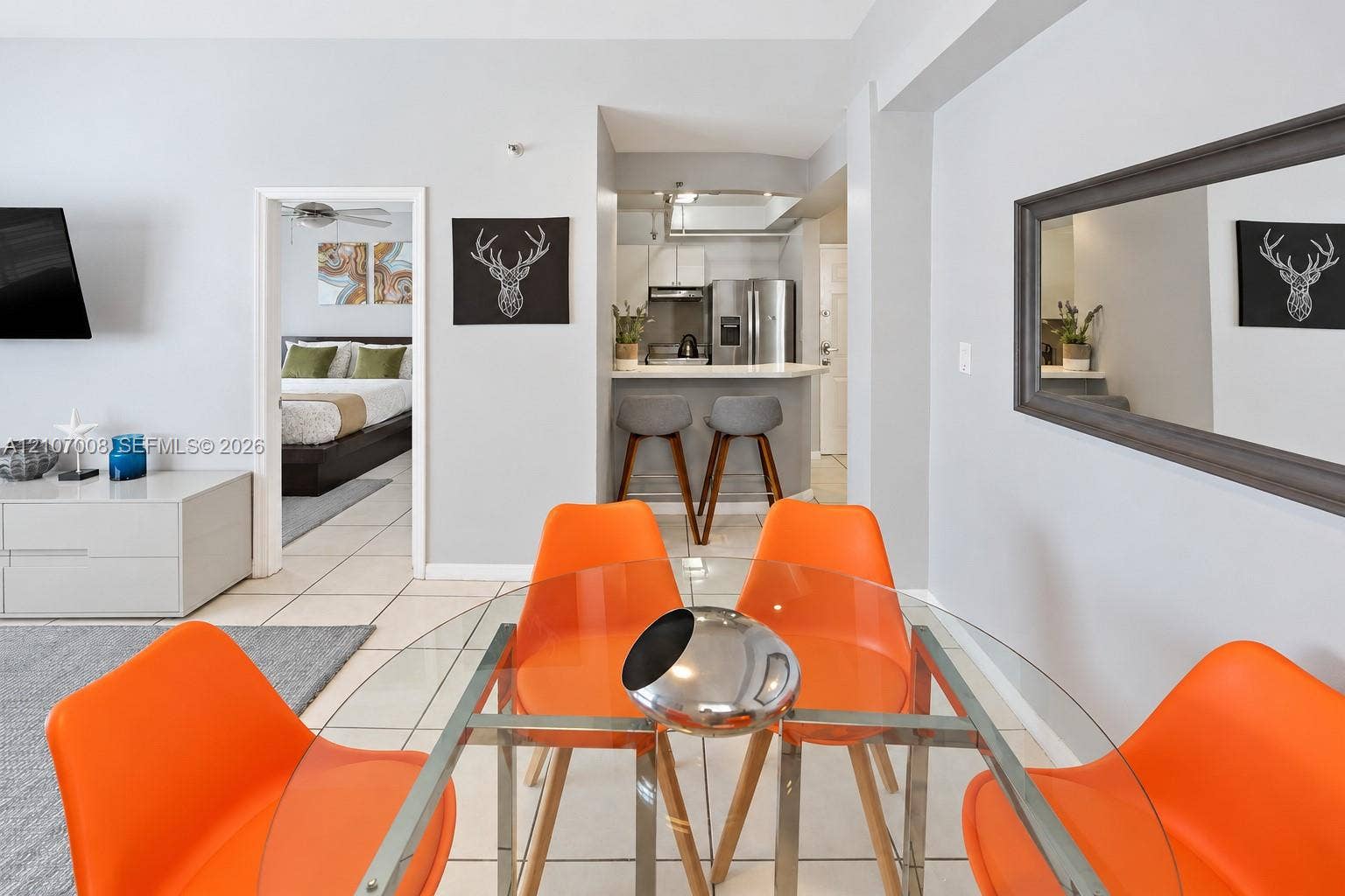 3030 Collins Avenue, #2H, Miami Beach, FL 33140 Open-concept interior featuring large-format tile flooring, kitchen with stainless steel appliances, breakfast bar, and wall-mounted mirror