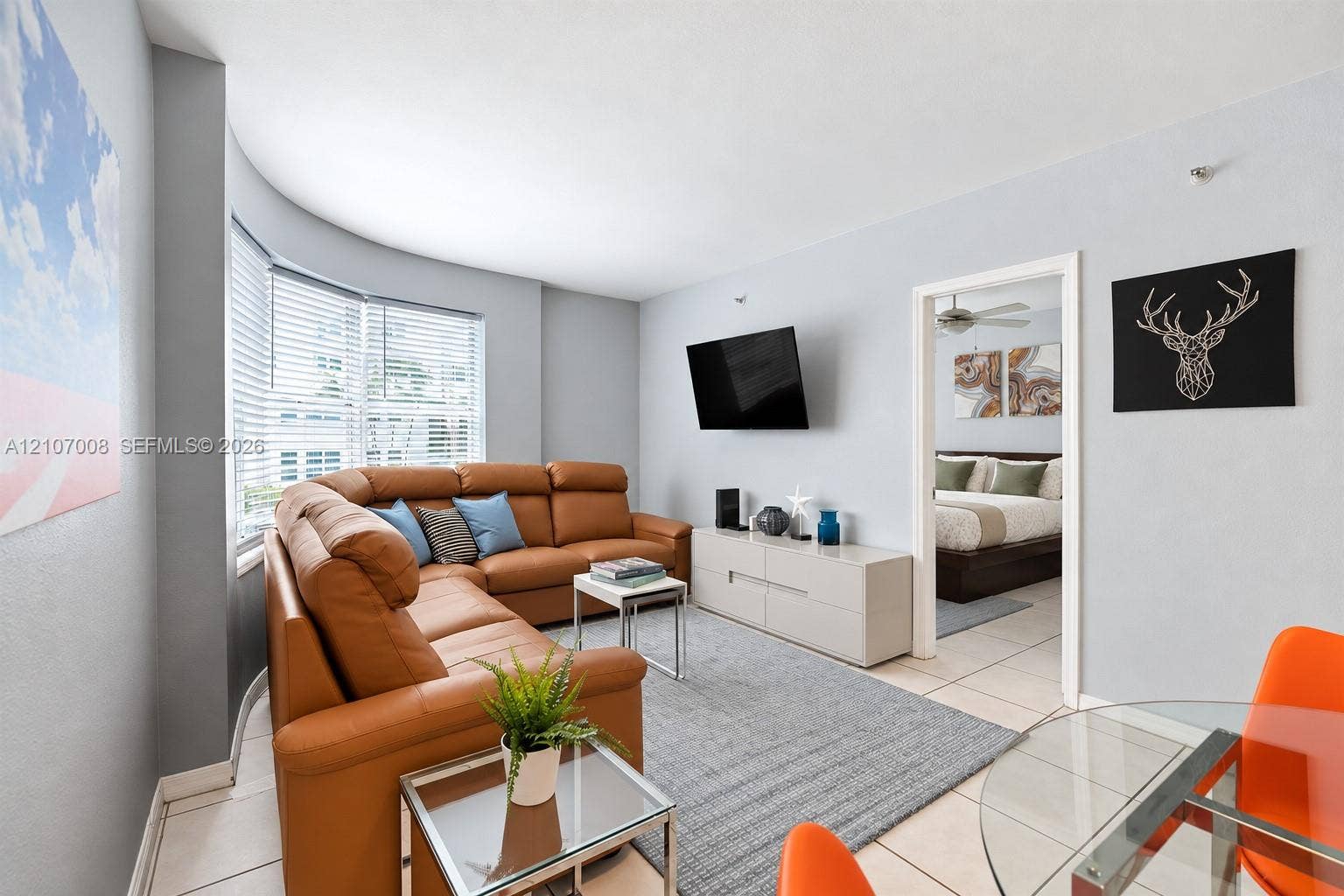 3030 Collins Avenue, #2H, Miami Beach, FL 33140 Living space featuring neutral ceramic tile flooring and a multi-panel bay window with horizontal blinds