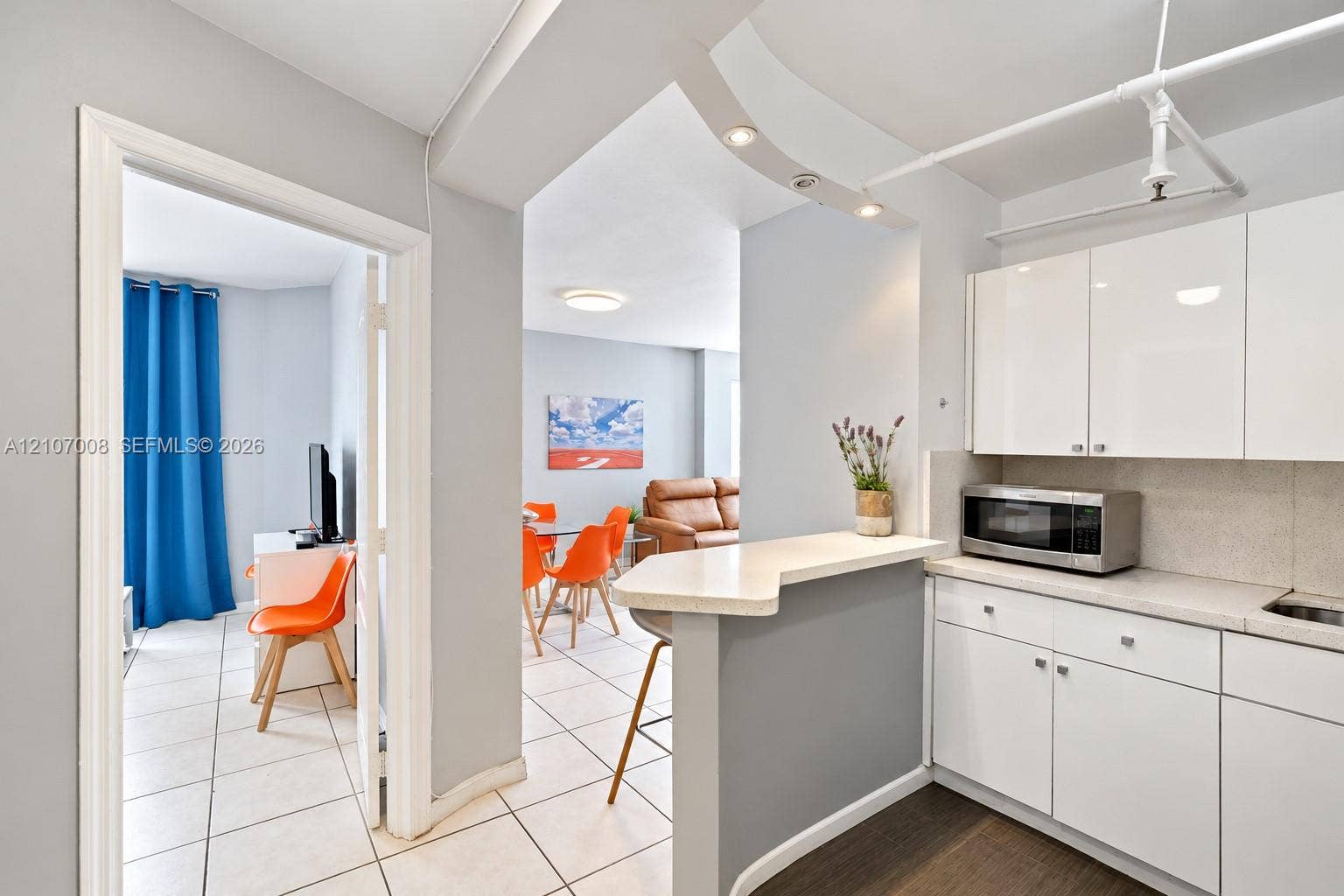 3030 Collins Avenue, #2H, Miami Beach, FL 33140 Kitchen featuring high-gloss white cabinetry, stone-finish countertops, a breakfast bar, recessed lighting, and tile flooring