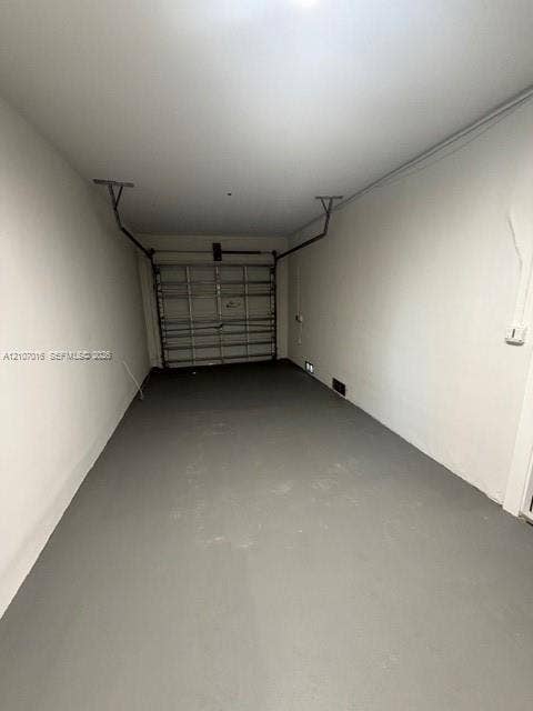 Enclosed space featuring a painted concrete floor, neutral wall finishes, and a sectional metal garage door