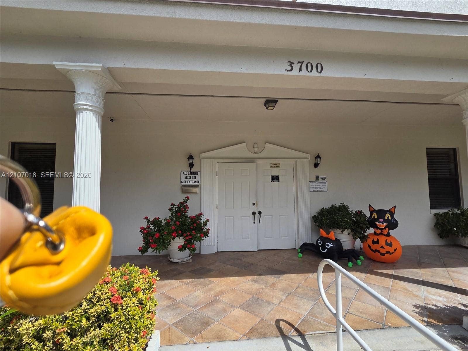 3716 Whitehall Drive, #304, West Palm Beach, West Palm Beach, FL 33401 Covered entryway featuring decorative fluted columns, a tiled porch, and double-door entry with architectural molding