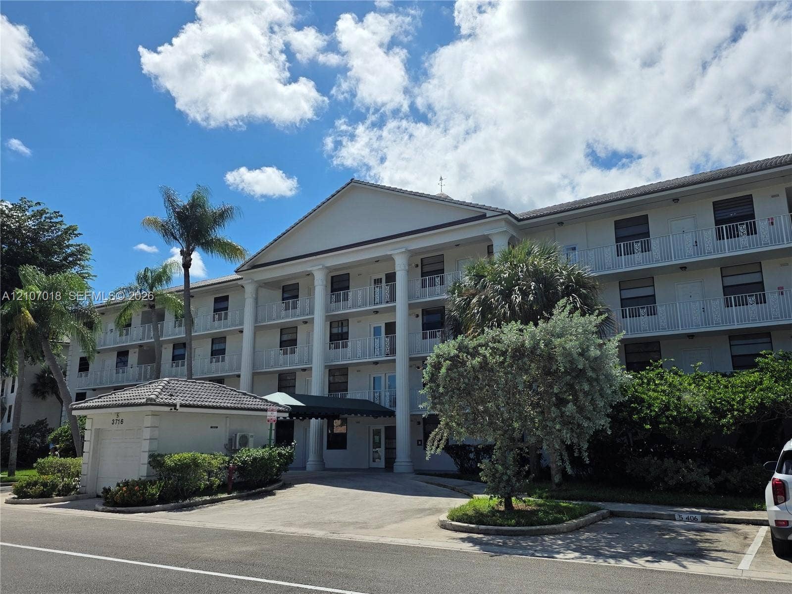3716 Whitehall Drive, #304, West Palm Beach, West Palm Beach, FL 33401 Multi-story building exterior featuring a prominent pedimented portico with classical columns, private railed balconies, and a detached single-car garage