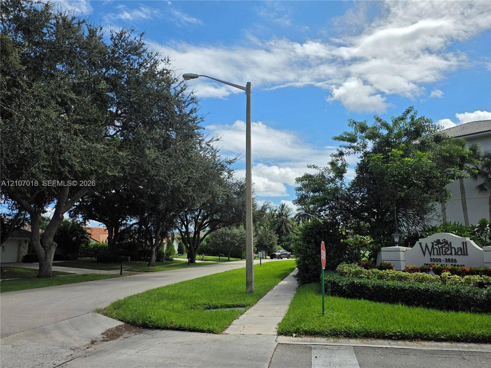 3716 Whitehall Drive, #304, West Palm Beach, West Palm Beach, FL 33401 Community entrance featuring mature shade trees, manicured landscaping, concrete sidewalks, and decorative monument signage