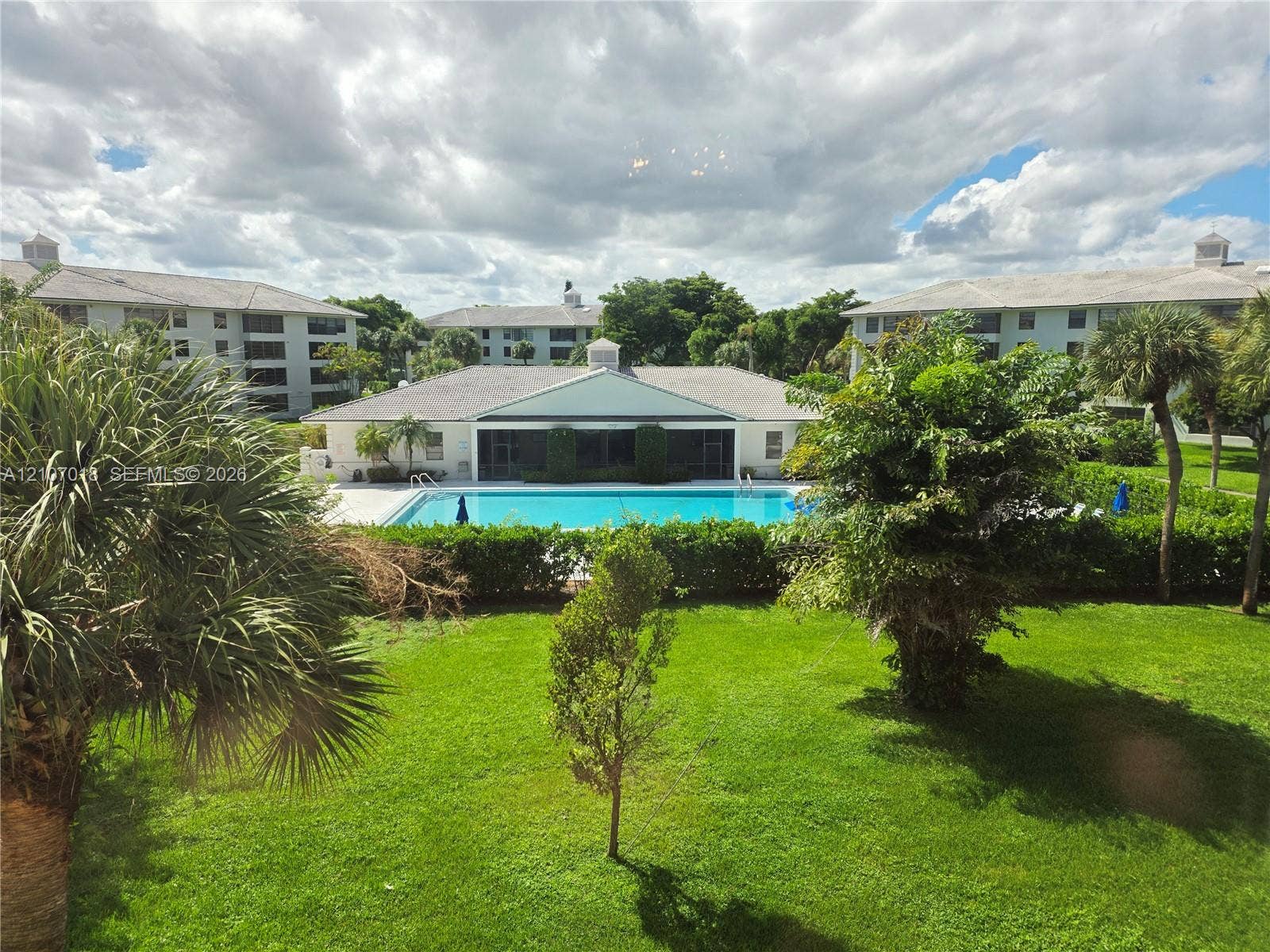 3716 Whitehall Drive, #304, West Palm Beach, West Palm Beach, FL 33401 Outdoor swimming pool surrounded by landscaped lawn, mature palms, and structured shrubbery