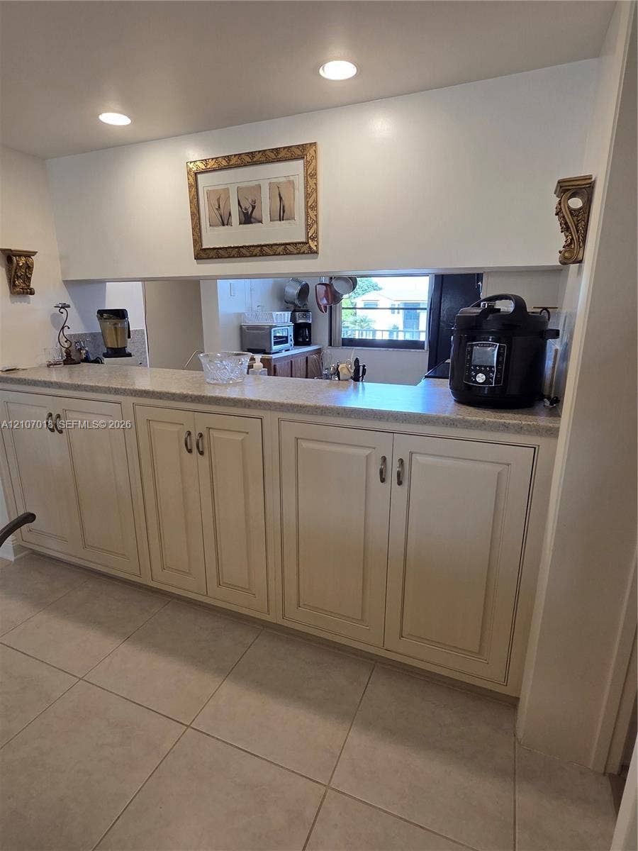 3716 Whitehall Drive, #304, West Palm Beach, West Palm Beach, FL 33401 Built-in cabinetry with off-white panel doors, neutral solid-surface countertop, recessed ceiling lighting, and large-format ceramic tile flooring