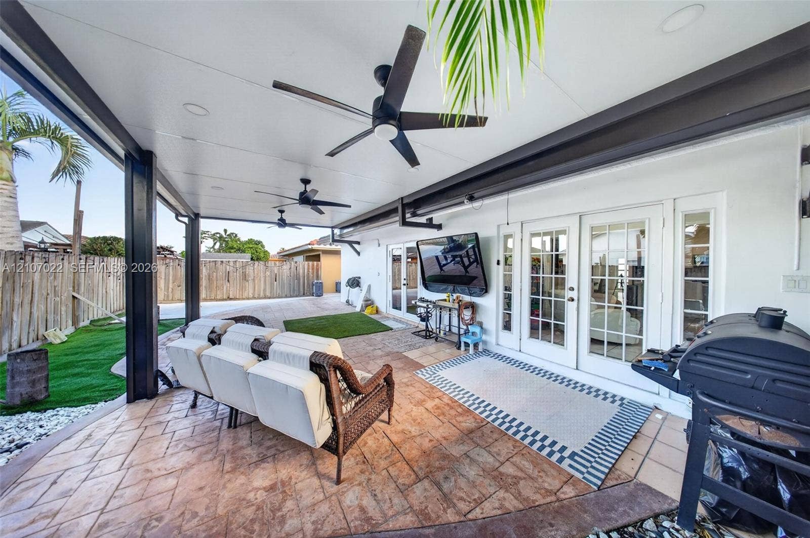 Covered outdoor patio featuring a stamped concrete floor, recessed ceiling lighting, dual ceiling fans, and multi-light French doors