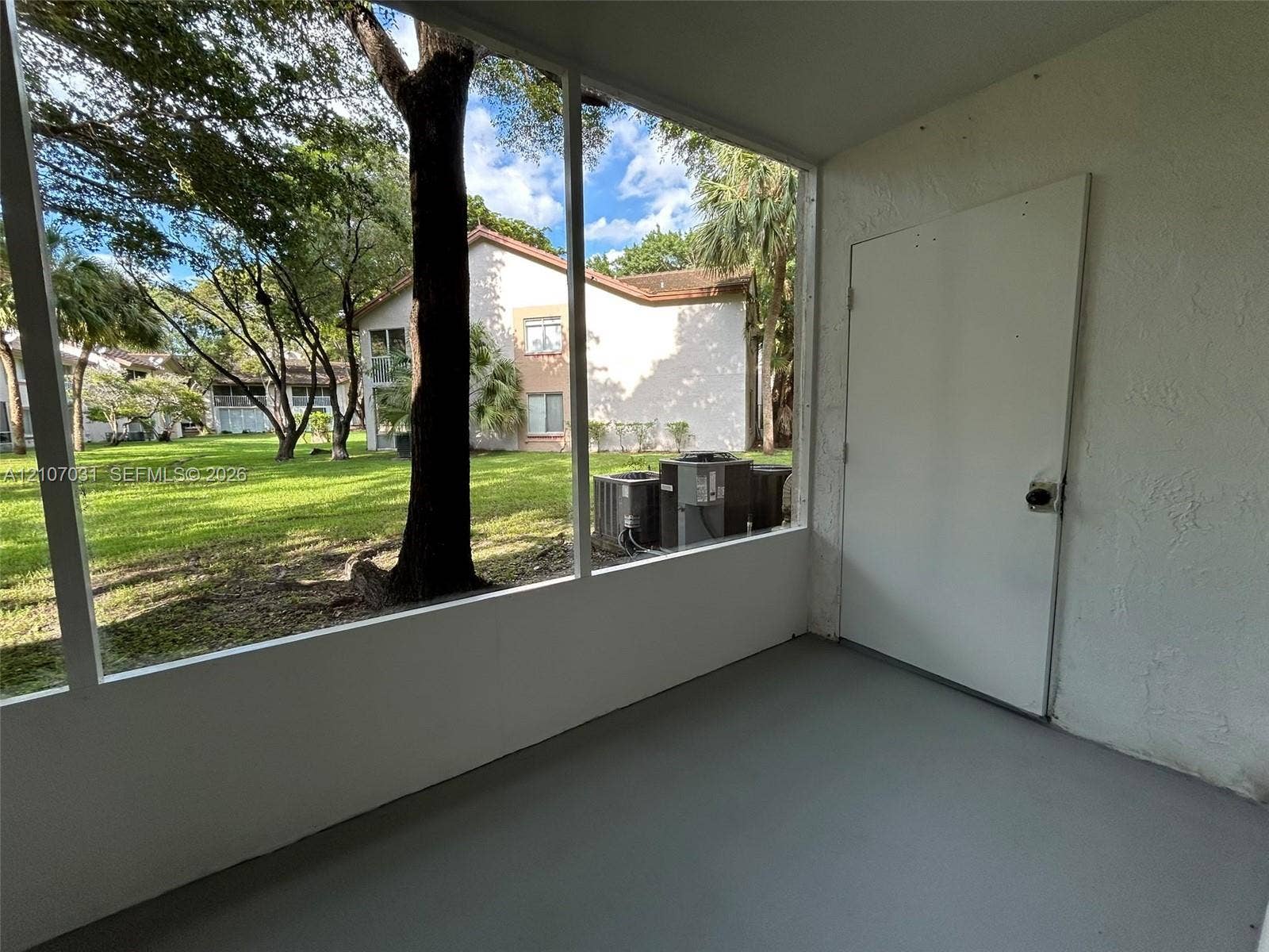 Screened-in enclosure featuring concrete flooring, a solid-core utility door, and wide-span mesh screening