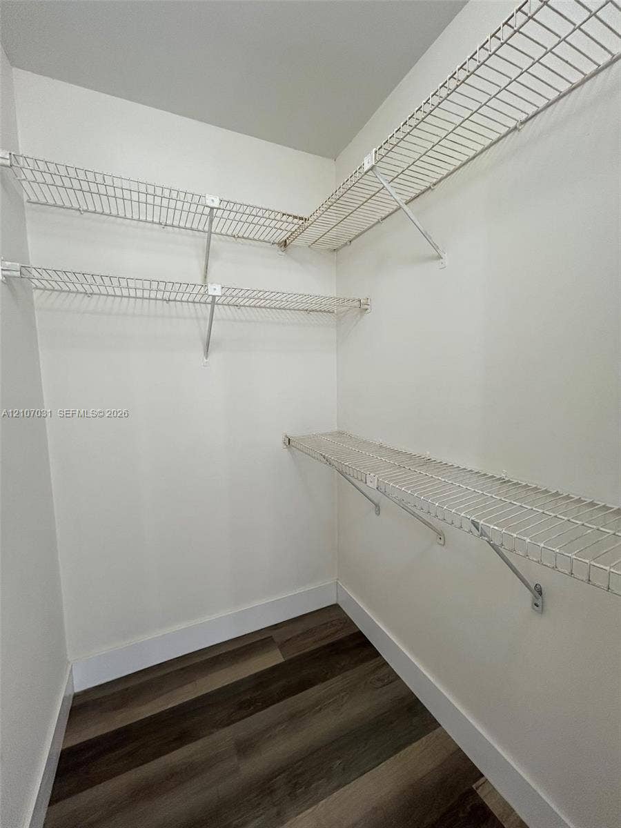 Storage space featuring multi-level white wire shelving and wood-finish flooring