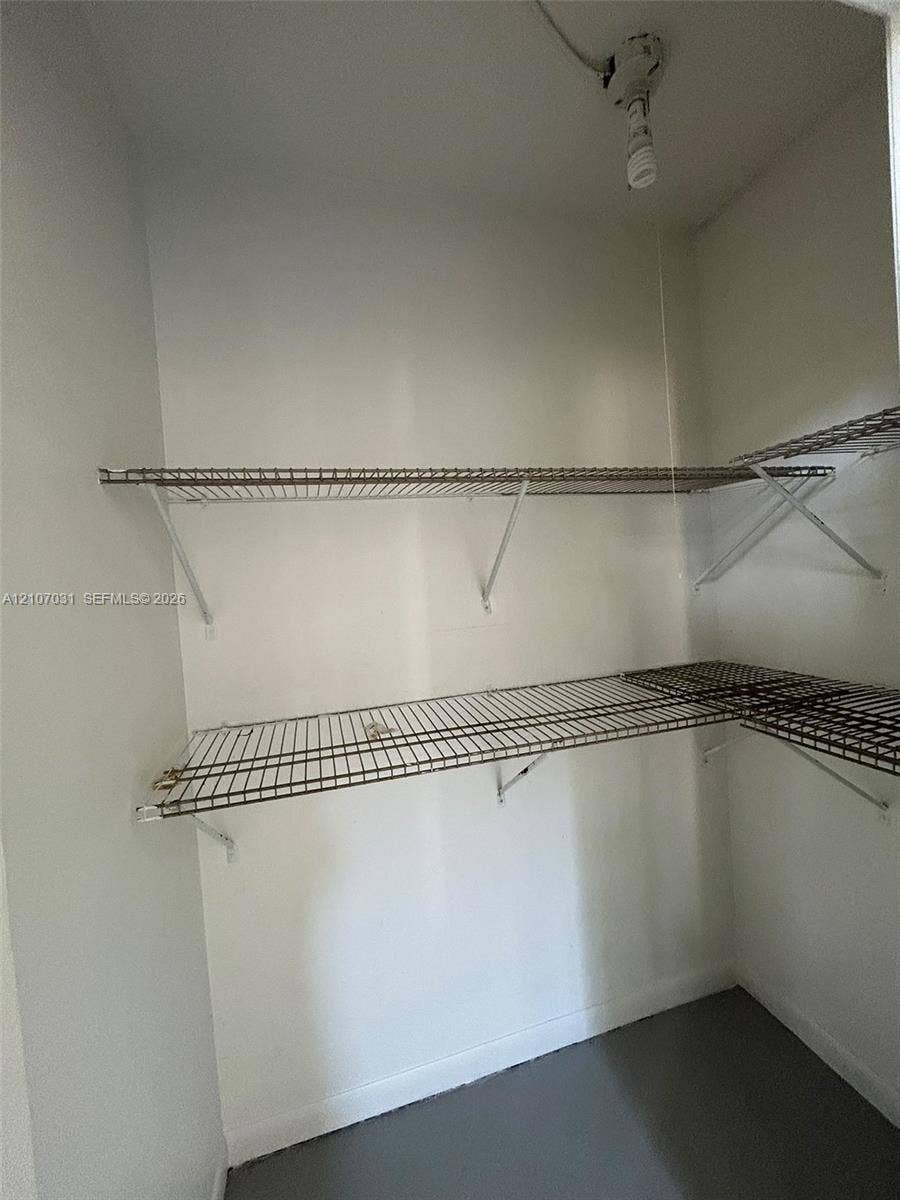 Built-in storage space featuring two levels of white wire shelving and a ceiling-mounted light fixture