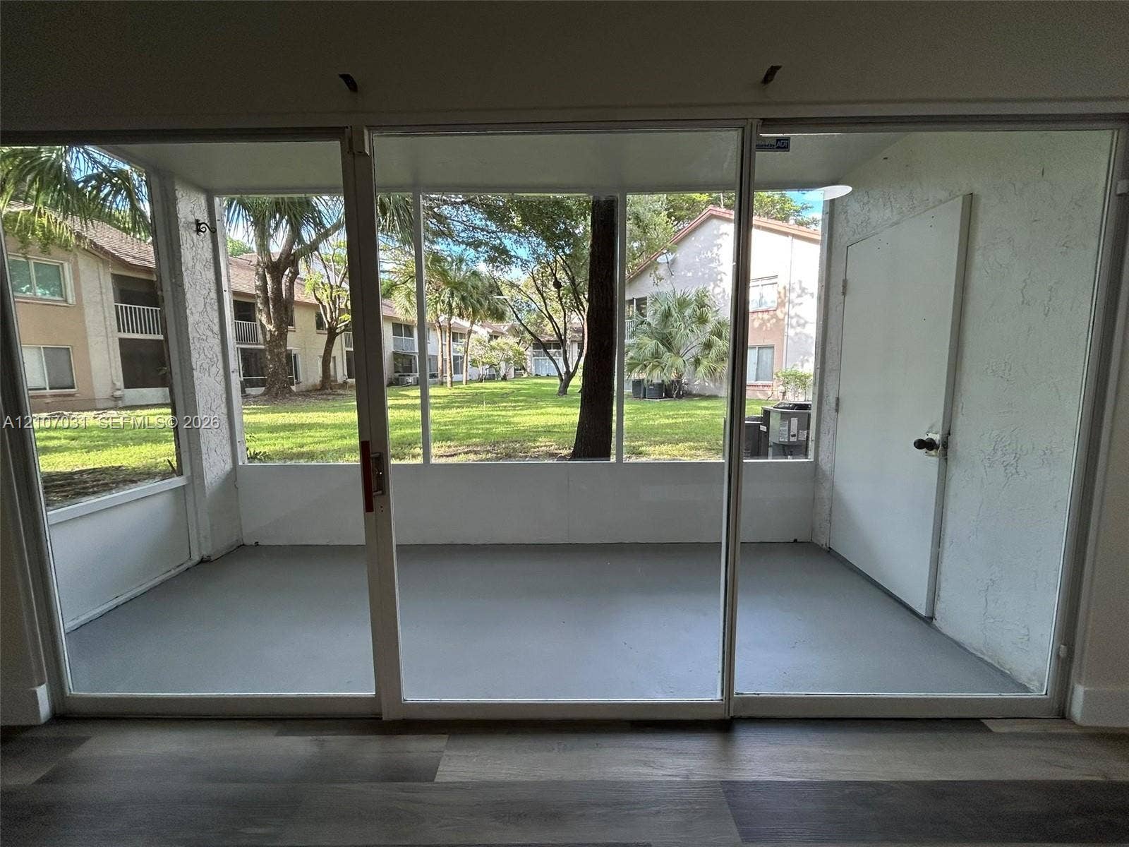 Enclosed porch featuring screen wall panels, painted concrete flooring, and a dedicated storage door