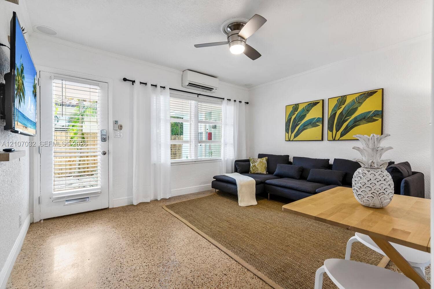 443 NE 17th Way, Fort Lauderdale, FL 33301 Neutral-toned aggregate flooring, brushed nickel ceiling fan with integrated lighting, wall-mounted ductless climate control unit, and glass-paneled exterior door